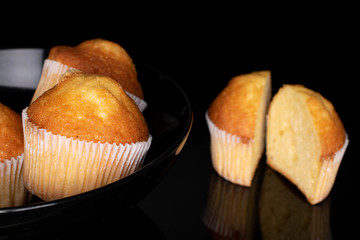 Group of three whole two halves of small baked muffin isolated on black glass