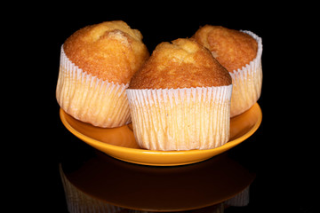 Group of three whole small baked muffin on plate isolated on black glass