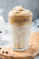 Dalgona frothy coffee in glass on grey. Trend korean drink latte with foam of instant coffee. Close up.