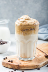 Dalgona frothy coffee in glass on grey. Trend korean drink latte with foam of instant coffee. Close up.