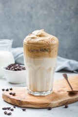 Dalgona frothy coffee in glass on grey. Trend korean drink latte with foam of instant coffee. Close up.