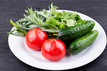 Plate with vegetables fresh, tomatoes and cucumbers with greens