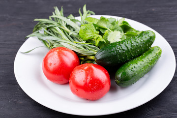 Plate with vegetables fresh, tomatoes and cucumbers with greens