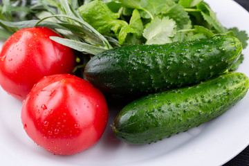 Plate with vegetables fresh, tomatoes and cucumbers with greens