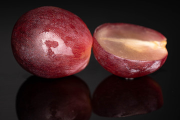Group of one whole one half of fresh red globe grape berry isolated on black glass