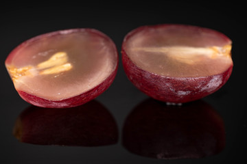 Group of two halves of fresh red globe grape berry isolated on black glass