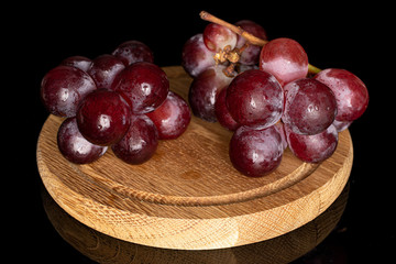 Lot of whole fresh red globe grape on wooden plate isolated on black glass