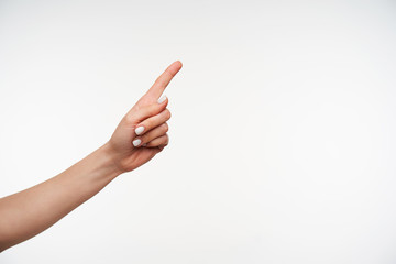 Indoor shot of young pretty fair-skinned female's hand keeping index finger raised while pointing...