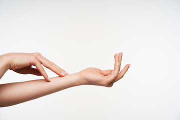 Side view of young elegant raised lady's hands touching each other gently while posing against...