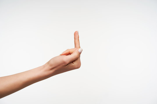 Side view young female's hand showing middle finger while meaning fuck you or fuck you off, posing over white background. Human signs and gesturing concept