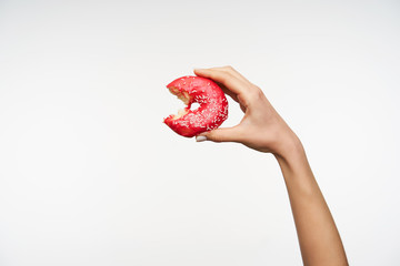 Delicious fresh donut being bitten and held by young woman with raised hand, isolated against white...