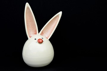 Schöner Osterhase aus Steingut vor schwarzem Hintergrund - schöne Dekoration zum Osterfest