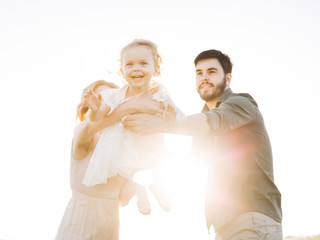 Happy family concept - father, mother and child daughter having fun and playing in nature.