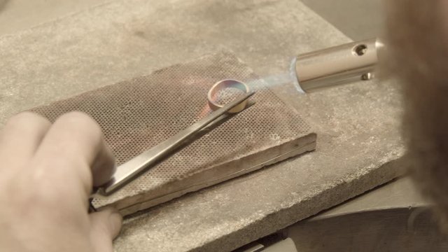 Goldsmith soldering a golden ring