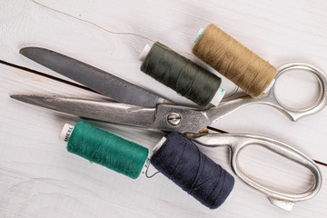 Sewing scissors with thread spools on white wood
