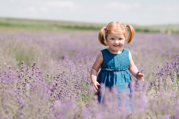 Happy little child in lavender. Kid walk, run in lavender, feeling nature. Baby girl playing and enjoying on a lavender meadow field background.