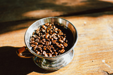 Coffee dripper with roasted coffee bean against  the sunlight in the morning. Top view of coffee dripper with roasted coffee bean on wooden background.