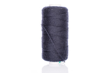 One whole dark blue thread spool isolated on white