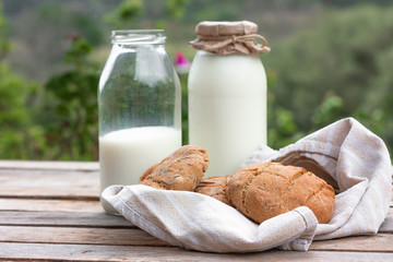 Fresh organic milk in a bottle and round brown rye flatbread on rustic wooden table on nature background. Vegetable milk, vegan milk, Kefir, or Turkish Ayran drink for helthy eating. Space for text