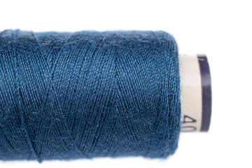 One whole blue thread spool closeup isolated on white