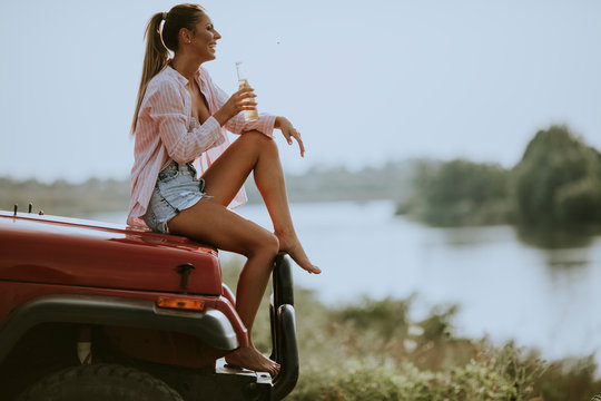 Happy Young Women Drinking Cider On The Vehicle At The Lakeside