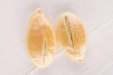 Group of two whole golden pumpkin seed macro on white wood