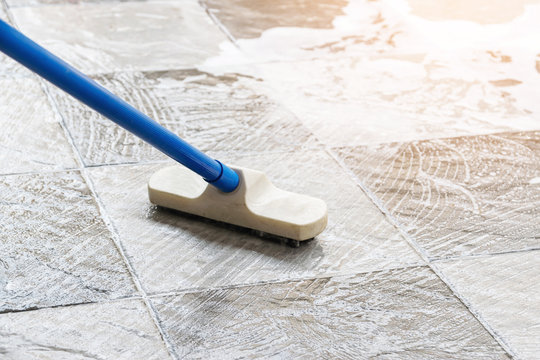 Cleaning the tile floor with floor scrubber brush and water.