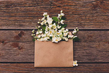 Jasmine flowers in an envelope on a wooden background.