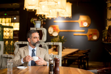 Thoughtful handsome mature businessman drinking coffee in cafe