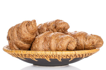 Lot of whole baked wholegrain croissant on plate with braided edge isolated on white