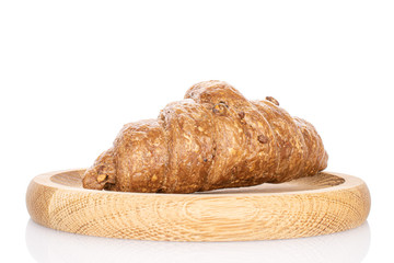 One whole baked wholegrain croissant on wooden plate isolated on white