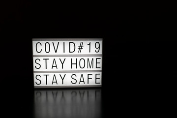 Picture of a light box with a message advice of coronavirus crisis with a black background isolated. Stay home message.