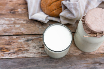 Glass of fresh milk and round brown rye flatbread on a rustic wooden table. Vegetable milk, vegan milk, Kefir, or Turkish Ayran drink for helthy eating. Space for text