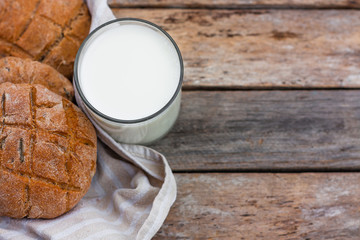 Glass of fresh milk and round brown rye flatbread on a rustic wooden table. Vegetable milk, vegan milk, Kefir, or Turkish Ayran drink for helthy eating. Space for text. Top view