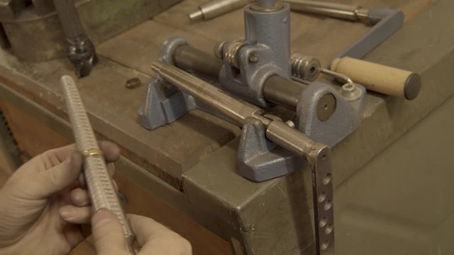 goldsmith measures a golden ring on a sizer gauge and uses size machine