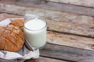 Glass of fresh milk and round brown rye flatbread on a rustic wooden table. Vegetable milk, vegan milk, Kefir, or Turkish Ayran drink for helthy eating. Space for text