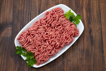 ground meat on white dish on brown wooden background