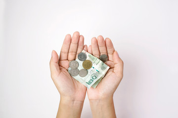 Hand holding Thai currency twenty baht banknote and coins on white background, Spend economically                                 