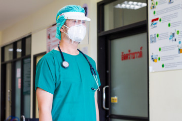 Doctor on face shield and N95 mask working hospital background