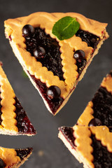 Levitating pieces of shortcrust pie with black currant. Dark key food photo. Pie on a black background. 