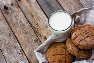 Glass of fresh milk and round brown rye flatbread on a rustic wooden table. Vegetable milk, vegan milk, Kefir, or Turkish Ayran drink for helthy eating. Space for text. Top view