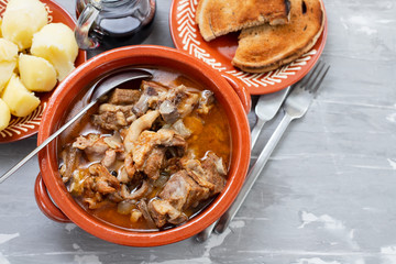 baked lamb with onion and pepper in the brown ceramic bowl