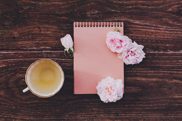 Blank craft sketchbook with pink flowers on wooden table.