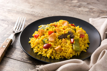 Fried rice with chicken and vegetables on black plate on wooden table