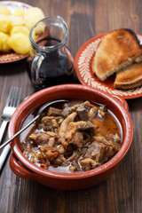 baked lamb with onion and pepper in the brown ceramic bowl