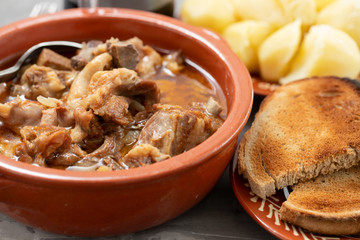 baked lamb with onion and pepper in the brown ceramic bowl