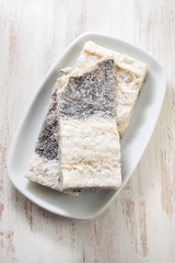 dry cod fish on white dish on old white wooden background