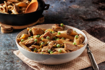 Homemade pasta with green peas, chicken and sauce on a dark background