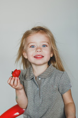 cute European blonde girl eating strawberries. a bright smile and healthy teeth. open view