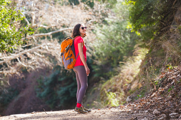 A girl with a backpack goes along a mountain trail.